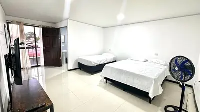 a bedroom with two beds and a fan in it at Marianas Apartments 5MIN SJO AIRPORT in Alajuela City