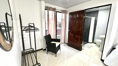 a room with a black chair and a bathroom at Marianas Apartments 5MIN SJO AIRPORT in Alajuela City