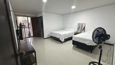 a bedroom with two beds and a fan at Marianas Apartments 5MIN SJO AIRPORT in Alajuela City