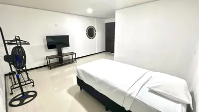 a white bedroom with a bed and a television at Marianas Apartments 5MIN SJO AIRPORT in Alajuela City