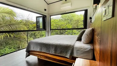 a bedroom with a bed and two large windows at Casa Ker Lumar in Uvita