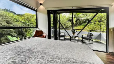 a bedroom with a large bed and large windows at Casa Ker Lumar in Uvita