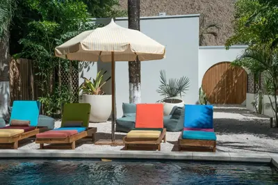 a group of chairs and an umbrella next to a pool at The Beach Break Surf Hotel in Nosara