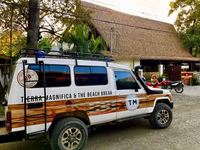 a white jeep parked in front of a building at The Beach Break Surf Hotel in Nosara