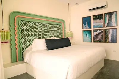 a bedroom with a white bed and two windows at The Beach Break Surf Hotel in Nosara