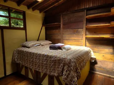 a bedroom with a bed in a room with wooden walls at Cloudbridge Nature Reserve in Herradura