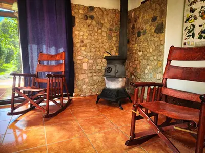 a living room with two chairs and a stove at Cloudbridge Nature Reserve in Herradura