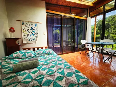 a bedroom with a bed and a table and chairs at Cloudbridge Nature Reserve in Herradura