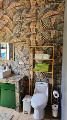a bathroom with a toilet and a wall with leaves at Nuevo Leones, #50 in Parrita