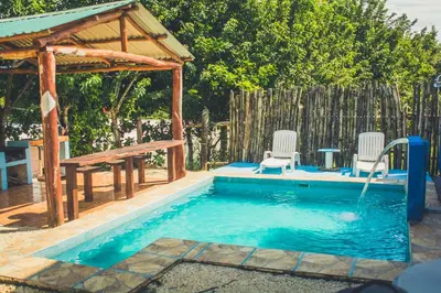 a swimming pool with two chairs and a wooden gazebo at Cabinas Cóbano - Florida in Tambor