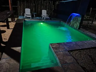 a green pool with a waterfall in a backyard at Villas Antomar in Puntarenas
