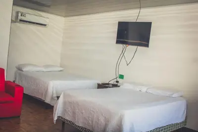a hotel room with two beds and a red chair at Villas Antomar in Puntarenas