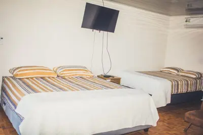 a bedroom with two beds and a tv on the wall at Villas Antomar in Puntarenas