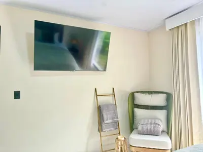 a bedroom with a chair and a tv on the wall at Arenal by the river in San Francisco