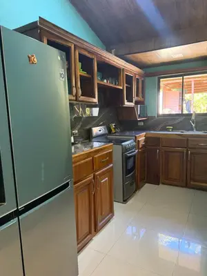 a kitchen with a stainless steel refrigerator and wooden cabinets at Casas DiTi in Santa Cruz
