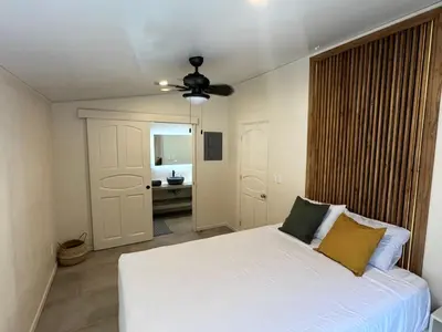 a bedroom with a white bed and a bathroom at Private Tail House centre Uvita in Uvita