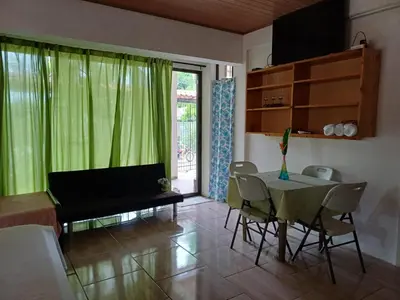 a living room with a table and a green curtain at Sol De Fati in Quepos