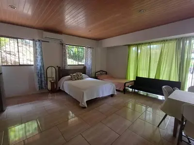 a bedroom with a bed and a couch and windows at Sol De Fati in Quepos