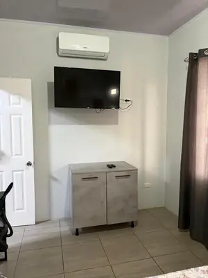 a room with a tv on a wall with a cabinet at Schultz Apartamento in Alajuela City