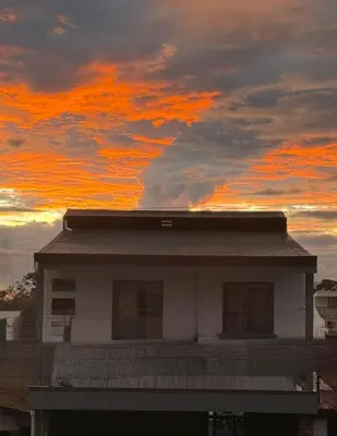 a house with a sunset in the background at Schultz Apartamento in Alajuela City