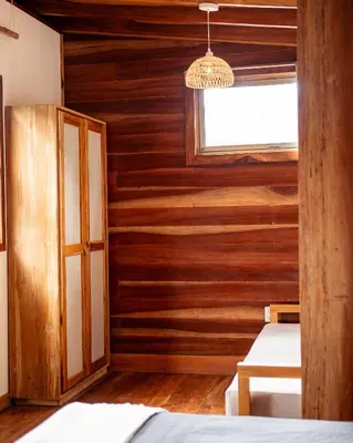 a room with wooden walls and a window and two beds at Casa Bismarkia in Santa Teresa Beach