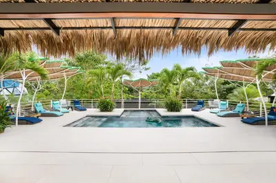 a resort pool with chairs and a thatched roof at Blue Ridge Retreat in Potrero