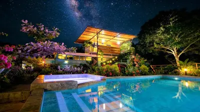 a house with a swimming pool at night at Bus Glamping near La Fortuna with Private Jacuzzi & Breakfast in Santa Clara