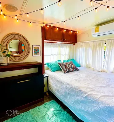 a bedroom with a bed and a mirror at Bus Glamping near La Fortuna with Private Jacuzzi & Breakfast in Santa Clara