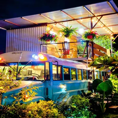 a blue bus parked inside of a building with plants at Bus Glamping near La Fortuna with Private Jacuzzi & Breakfast in Santa Clara