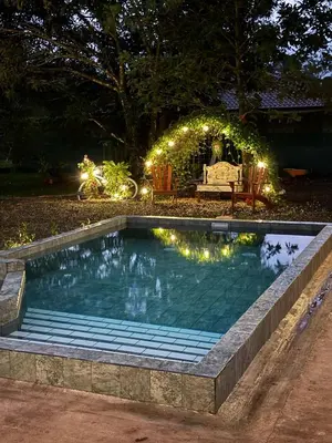 a swimming pool with lights in a backyard at night at Bus Glamping near La Fortuna with Private Jacuzzi & Breakfast in Santa Clara