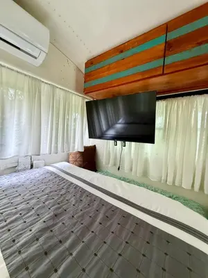 a bedroom with a bed with a flat screen tv at Bus Glamping near La Fortuna with Private Jacuzzi & Breakfast in Santa Clara