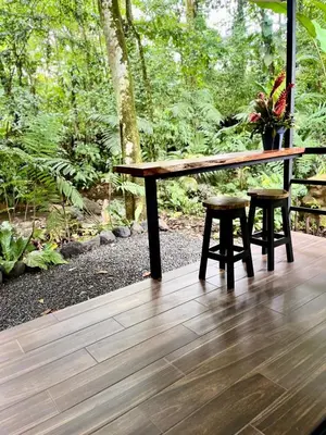 a wooden table and two stools on a wooden deck at Arenal Rocks in Fortuna
