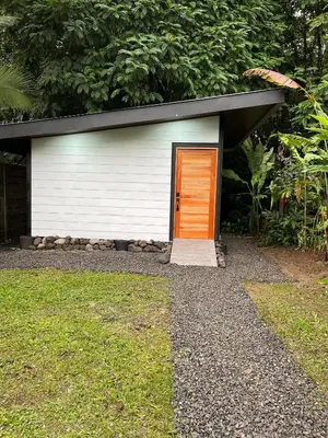 a white garage with an orange door in a yard at Arenal Rocks in Fortuna