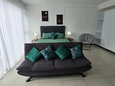 a bedroom with a bed and a couch with pillows at Tropical Vista iFreses, 2nd floor! AC, TV and Pool in Guayabos