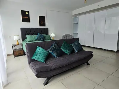 a couch with pillows on it in a living room at Tropical Vista iFreses, 2nd floor! AC, TV and Pool in Guayabos