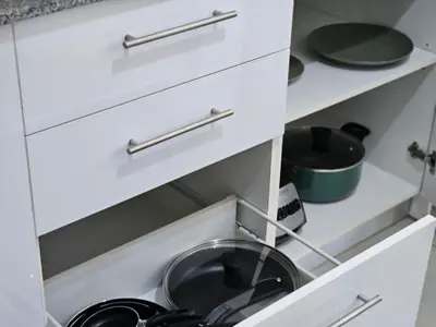 a white kitchen with a frying pan in a drawer at Tropical Vista iFreses, 2nd floor! AC, TV and Pool in Guayabos