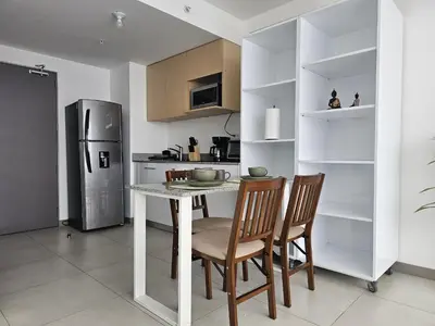a kitchen with a table and chairs and a refrigerator at Tropical Vista iFreses, 2nd floor! AC, TV and Pool in Guayabos