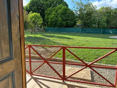 a view of a field through a red fence at Casa Elora in Bagaces