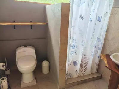 a bathroom with a toilet and a shower curtain at Casa Elora in Bagaces