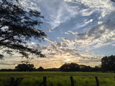 a field with a fence and a cloudy sky at Casa Elora in Bagaces