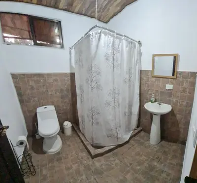 a bathroom with a shower curtain and a toilet and a sink at Casa Elora in Bagaces