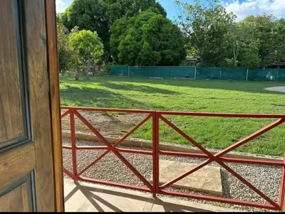 a view of a field through a red fence at Casa Elora in Bagaces