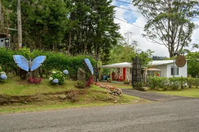 a house with a yard with butterfly statues and flowers at Blue Morpho Lodge in Bajos del Toro