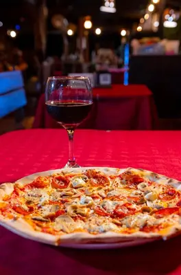 a pizza sitting on a table with a glass of wine at Cabinas La Fulanita in Nicoya