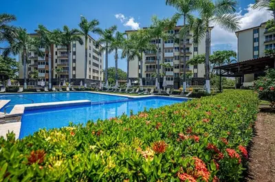 a pool at a resort with palm trees and flowers at 9-26 Costa Linda Jacó Beach pool view Balcony in Jacó