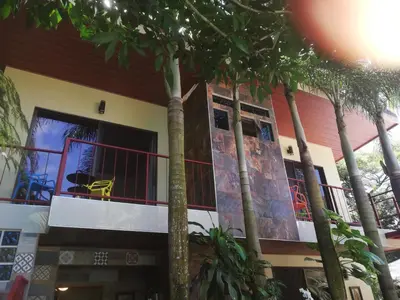 a building with palm trees in front of it at Coyaba Tropical Elegant Adult Guesthouse in Manuel Antonio