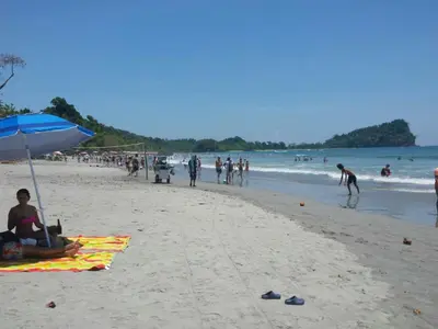 a group of people on a beach with an umbrella at Coyaba Tropical Elegant Adult Guesthouse in Manuel Antonio