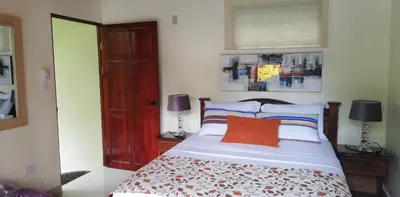 a bedroom with a bed with an orange pillow at Coyaba Tropical Elegant Adult Guesthouse in Manuel Antonio