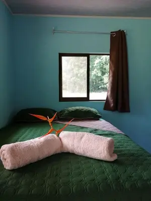 a bed with two towels on it with a window at Paz y Flora Cabins - 4x4 or 4x2 Car Only in Drake