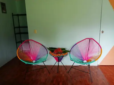three pink and green chairs sitting on a wooden floor at Paz y Flora Cabins - 4x4 or 4x2 Car Only in Drake